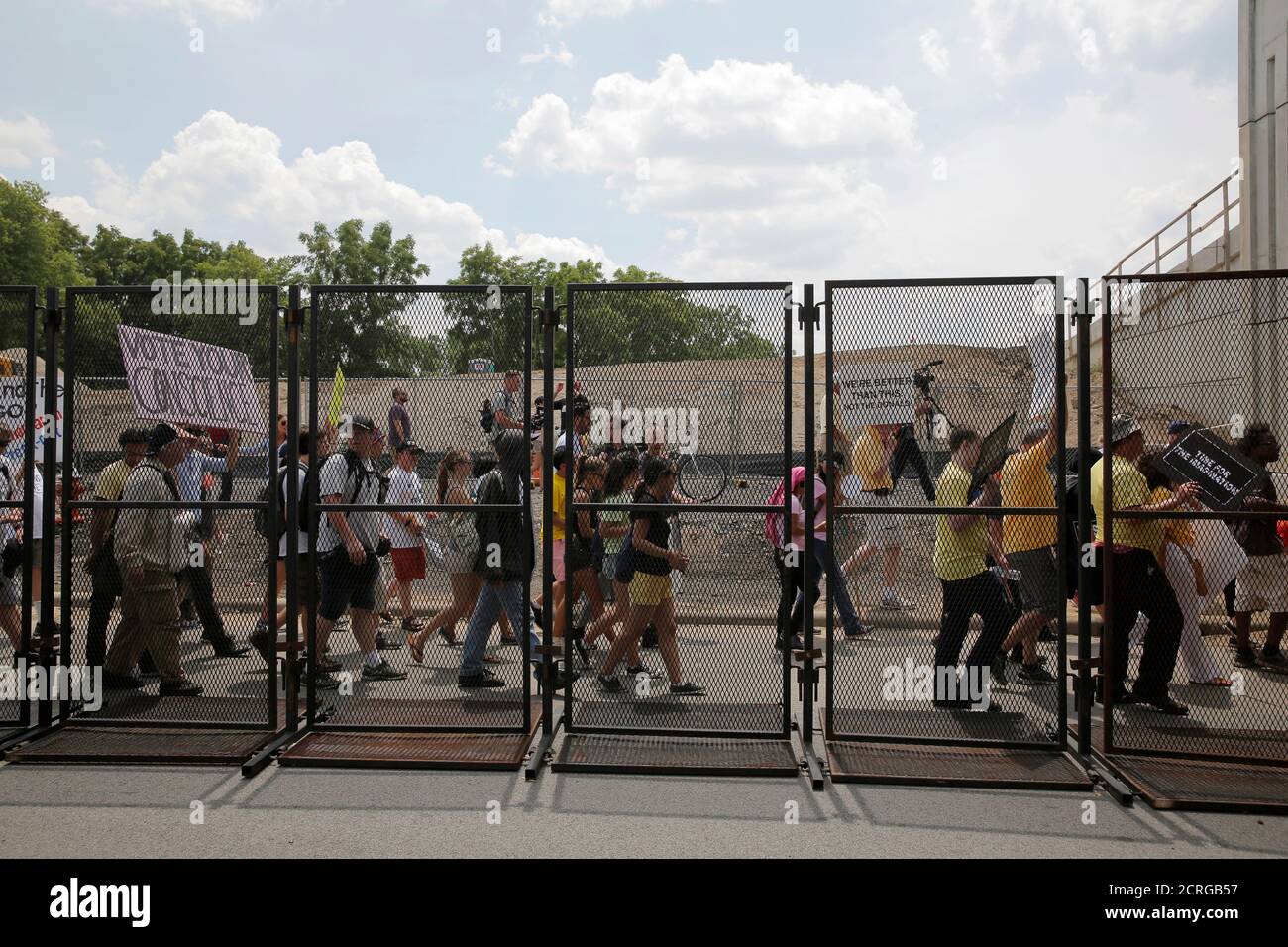 People walk behind a security fence during an anti-Trump protest to coincide with the Republican National Convention in Cleveland, Ohio, U.S., July 21, 2016.  REUTERS/Andrew Kelly Stock Photo