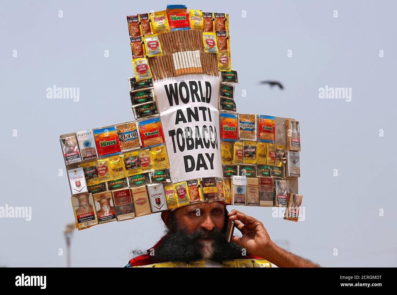 Rajendra Kumar Tiwari, a social activist, wearing a headgear made from empty cigarettes packets speaks on his mobile phone as he conducts an anti-tobacco awareness campaign to mark 'World No Tobacco Day' in Mumbai, India, May 31, 2018. REUTERS/Francis Mascarenhas Stock Photo