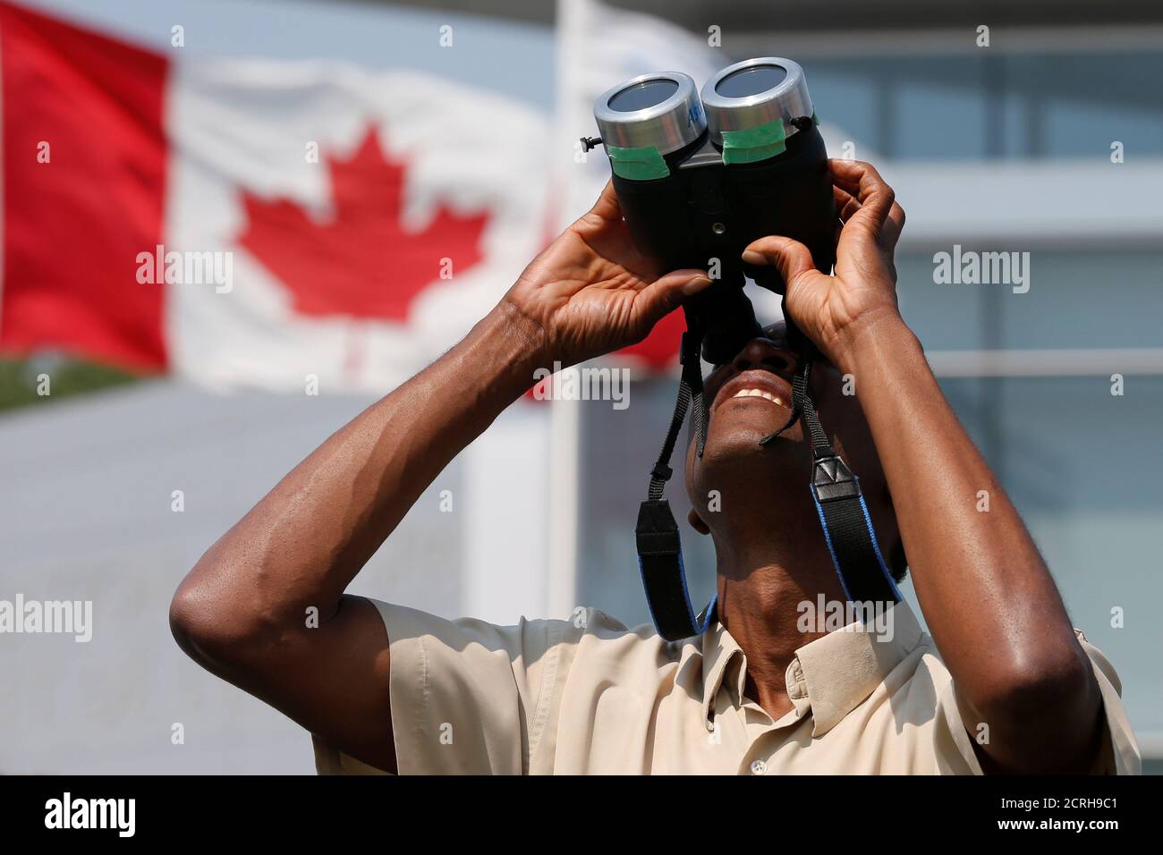A man uses binoculars to watch a partial solar eclipse at the Canada Aviation and Space Museum in Ottawa, Ontario, Canada, August 21, 2017. REUTERS/Chris Wattie Stock Photo
