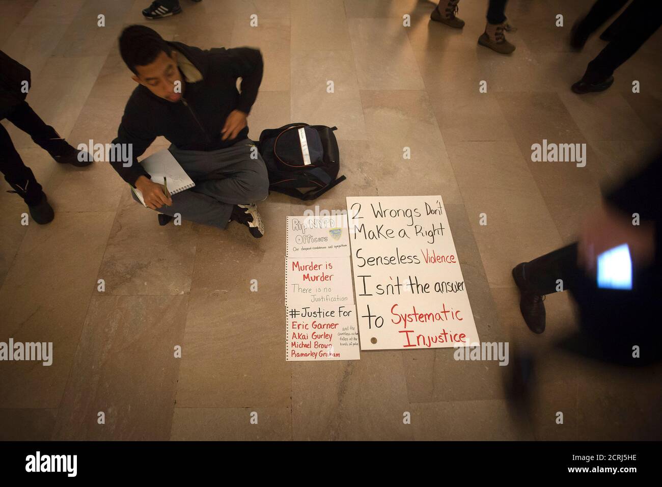 A lone protester sits on the floor of Grand Central Terminal to demonstrate against the police in the Manhattan borough of New York December 23, 2014. Mayor Bill de Blasio's attempts to soothe a city dismayed by the slaying of two officers were further rebuffed on Tuesday as protesters defied his call to suspend what have become regular demonstrations over excessive police force. REUTERS/Carlo Allegri (UNITED STATES - Tags: CIVIL UNREST CRIME LAW) Stock Photo