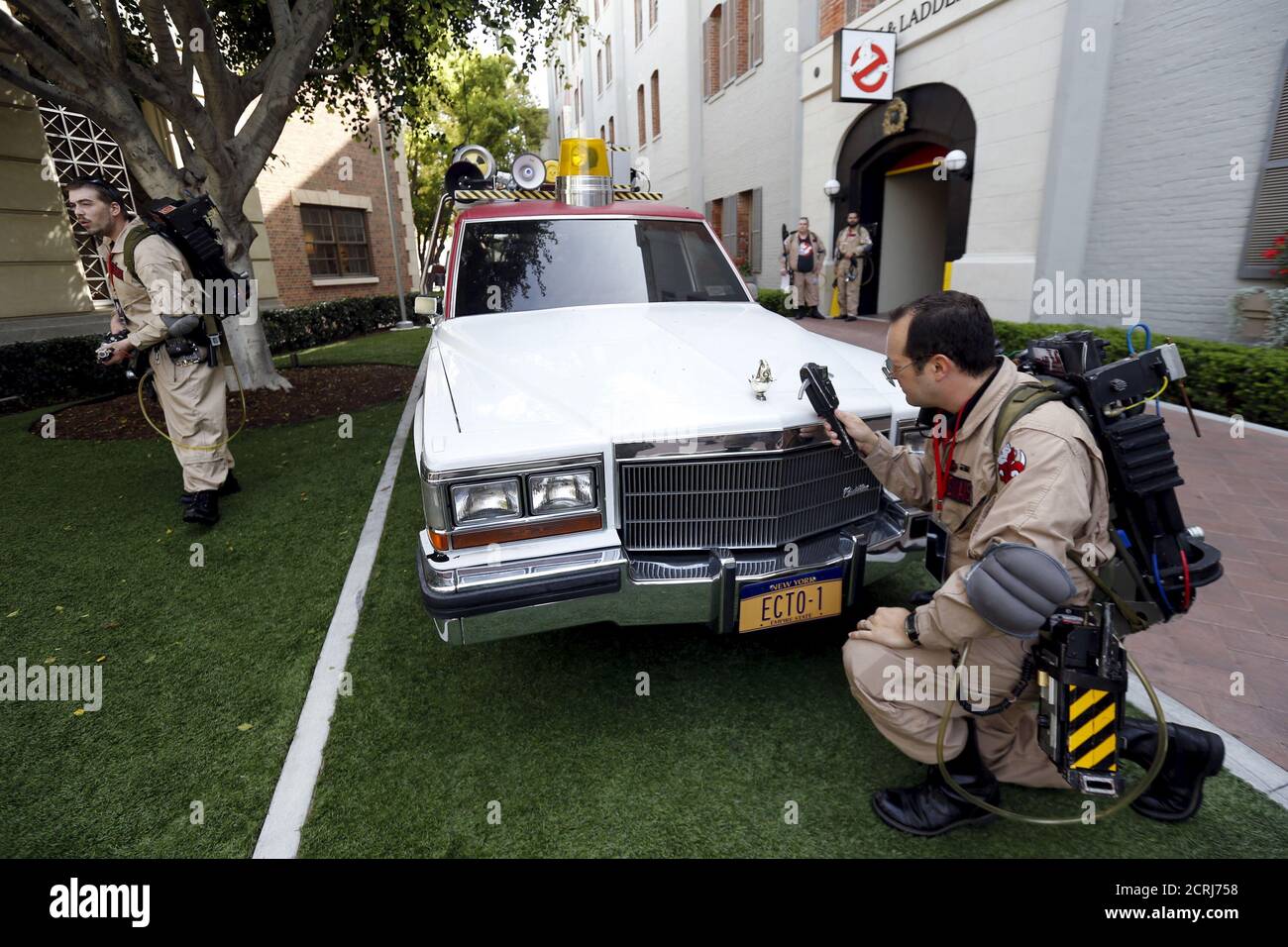 Enthusiasts wearing Ghostbusters costumes stand by an ECTO-1, the vehicle used in the upcoming movie 'Ghostbusters,' during a photo call at Sony Studios in Culver City, California March 2, 2016.    REUTERS/Mario Anzuoni Stock Photo