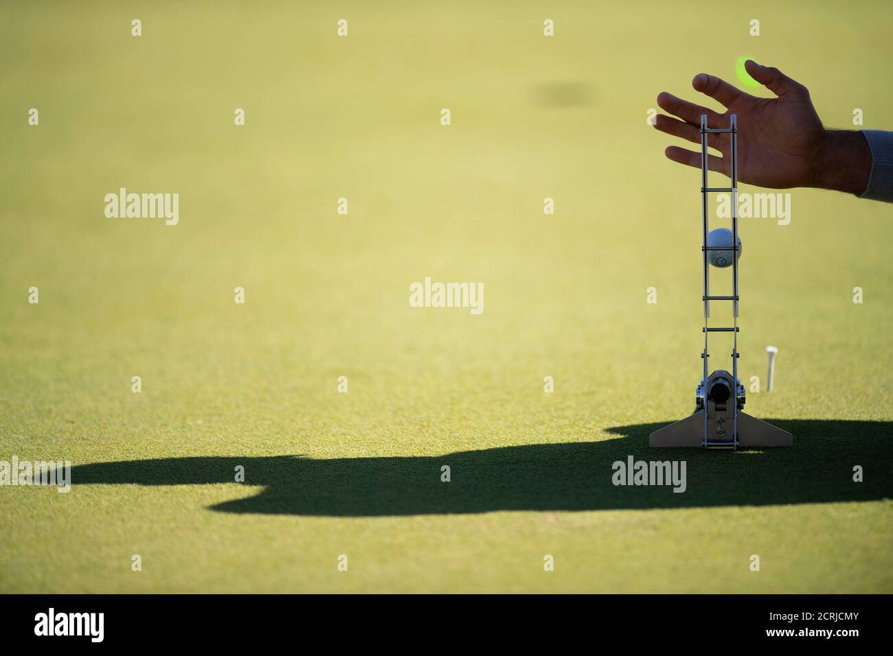 A caddie uses a laser putting device to measure the speed of the greens on the practice green during day two of the BMW PGA Championship at Wentworth Stock Photo