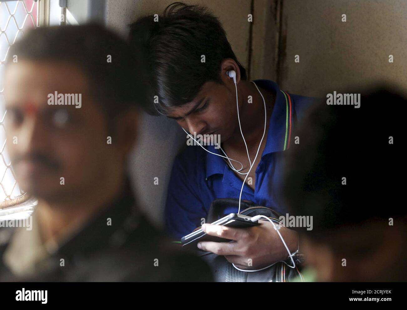 A man watches a video on his mobile phone as he commutes by a suburban train in Mumbai, India, March 31, 2016. With smartphone sales booming and India preparing for nationwide 4G Internet access, India's film and TV industry hopes the ease of tapping your phone for the latest release will generate profits at last, overcoming the problems of woefully few cinemas and rampant piracy. Picture taken March 31, 2016. REUTERS/Shailesh Andrade Stock Photo