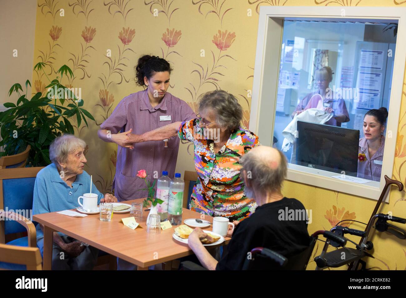 Alba Gil Quiros (2nd L) from the Spanish island of Tenerife assists a resident at the SenVital elderly home in Kleinmachnow outside Berlin May 28, 2013. Facing an acute shortage of skilled applicants among its own workforce, German institutions in the care sector increasingly turn to southern European countries to hire trained nursing staff who are willing to work abroad despite the language barrier in order to escape unemployment at home. The SenVital home for the elderly outside Berlin has accepted five qualified nurses from Spain as their staff, providing eight months of language training a Stock Photo