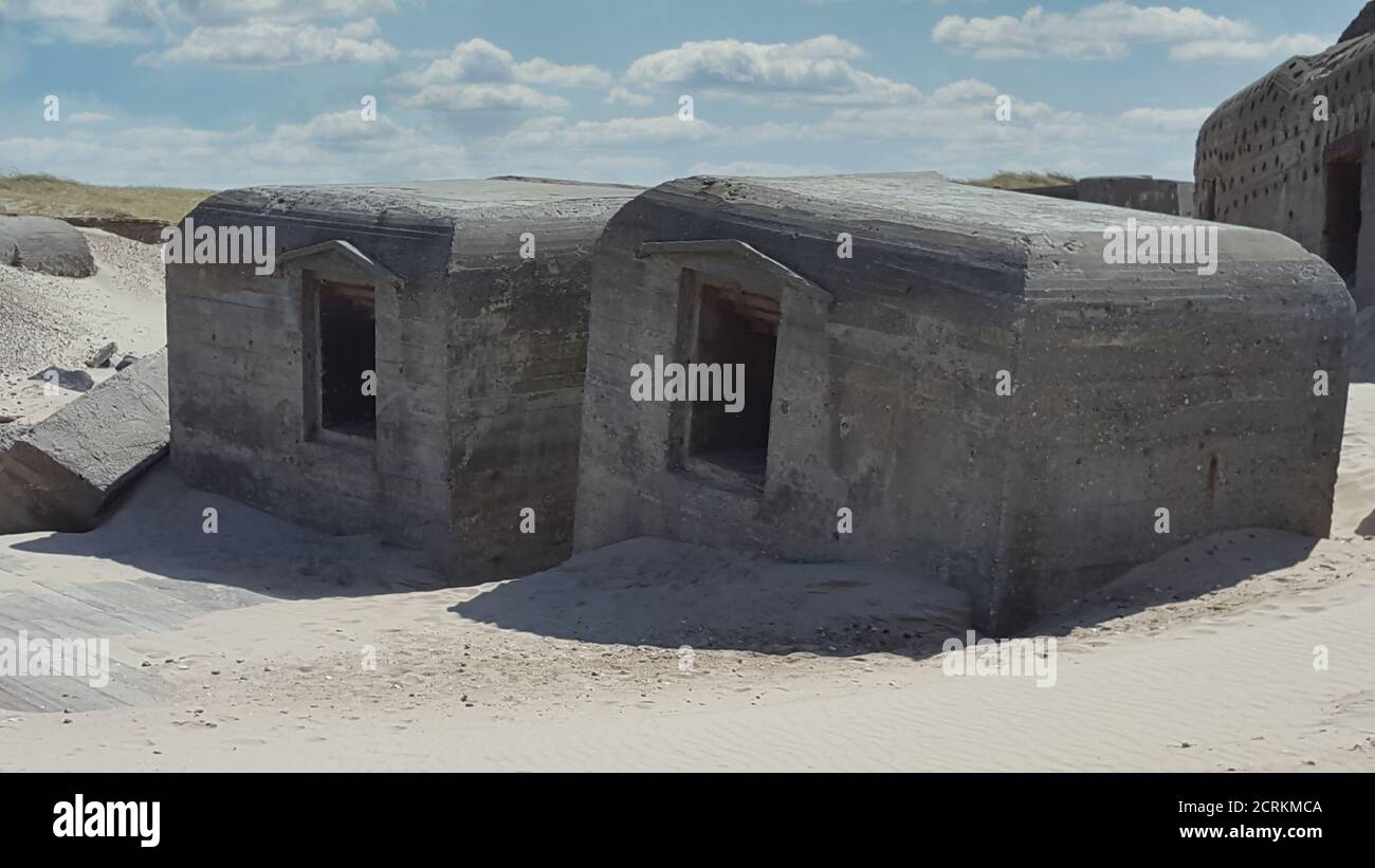 Sinister looking German World War 2 bunker in the dunes of the Atlantikwall against a clouded sky Stock Photo