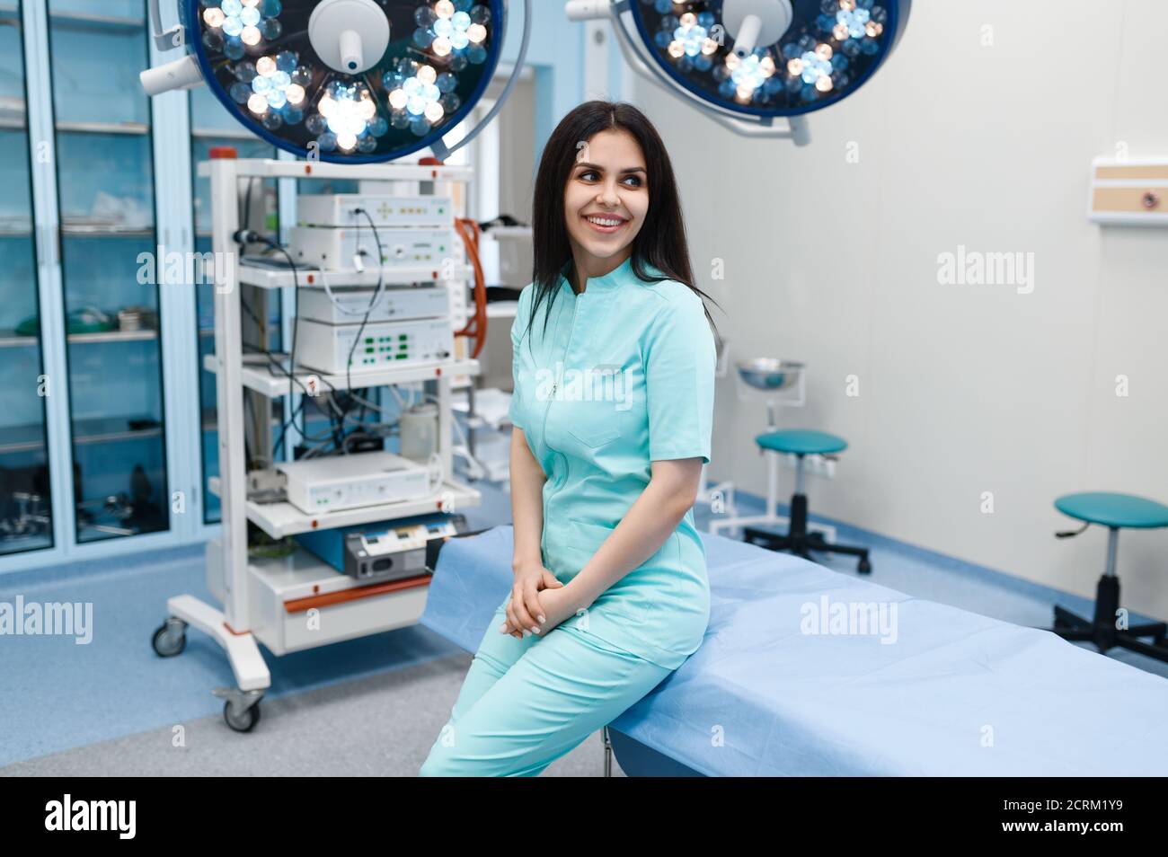 Smiling female surgeon poses at operating table Stock Photo