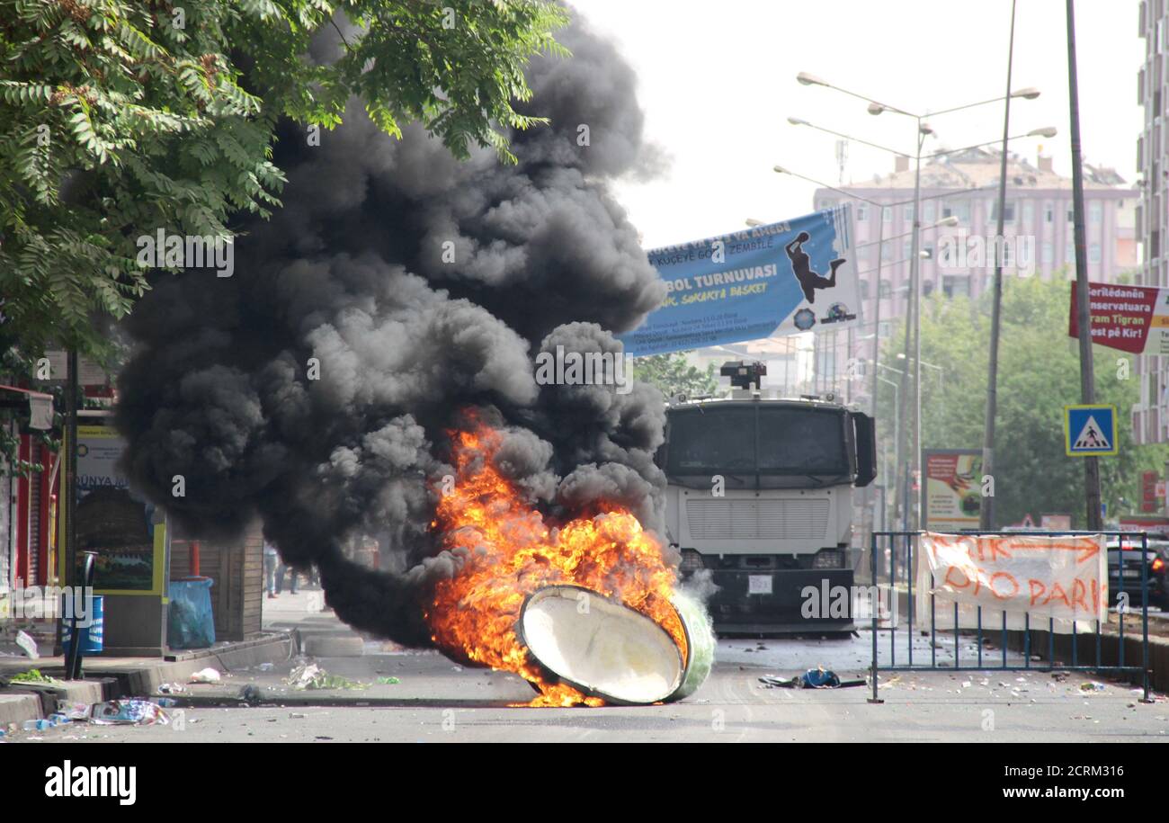 A trash can is set on fire by protesters before a police vehicle in the Kurdish dominated southeastern city of Diyarbakir, Turkey, September 13, 2015. Kurdish militants on Sunday killed two police officers when they bombed a checkpoint in Sirnak in southeast Turkey and a curfew was imposed in central Diyarbakir, the region's largest city, after clashes there, security sources and officials said. In Diyarbakir, the historic Sur district was put under curfew and seven police officers were wounded in clashes with militants there, the governor's office said. REUTERS/Sertac Kayar Stock Photo