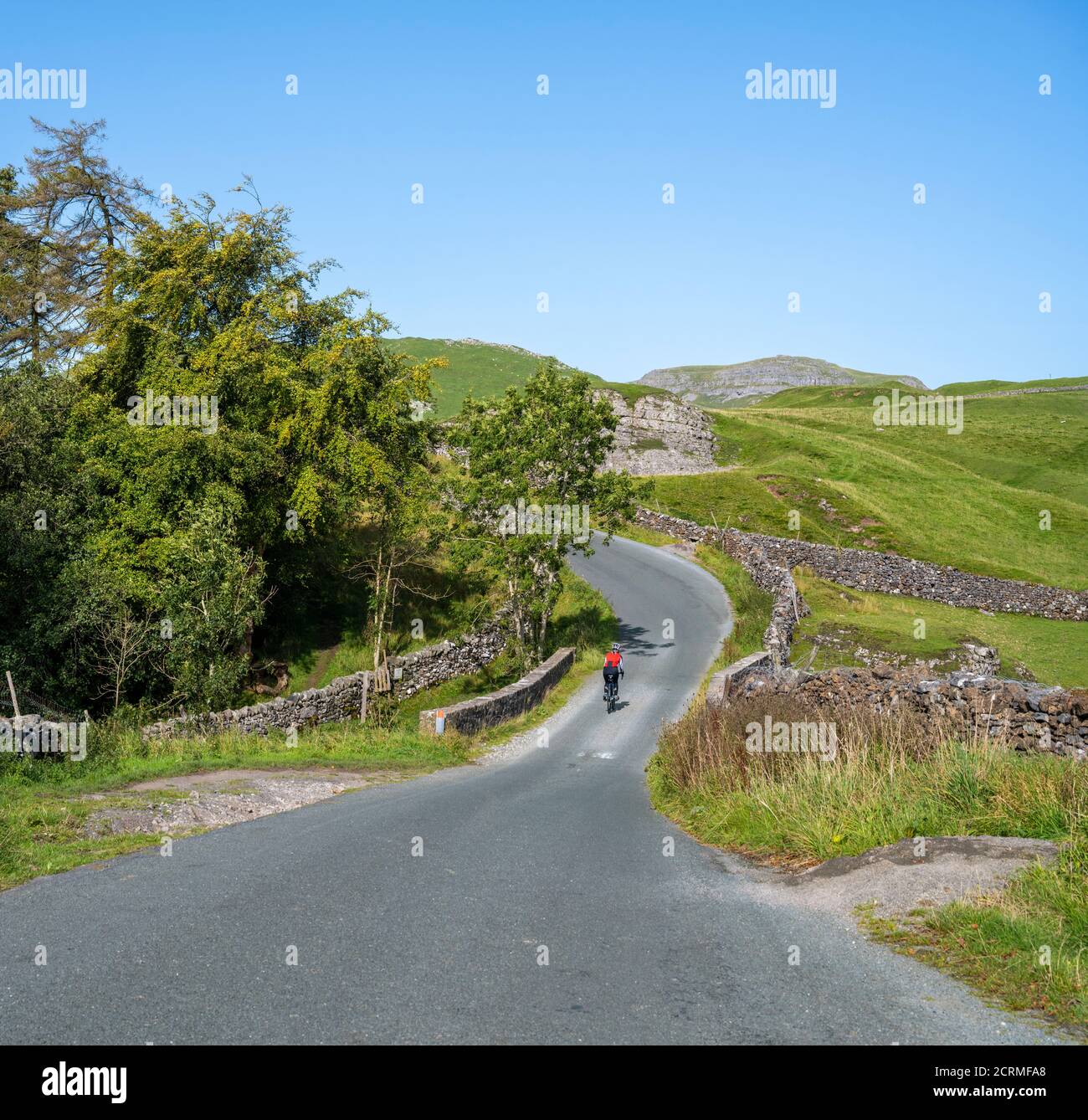 Female cyclist riding the fell road between Airton and Settle in the Yorkshire Dales, UK. Stock Photo