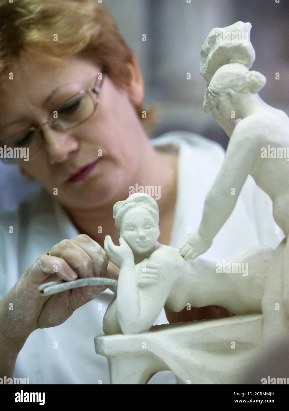 A woman works on a clay figure that is to be used to cast porcelain sculptures in the Dulevo Porcelain factory in the town of Dulevo, about 115 km (73 miles) from Moscow February 20, 2009. A Tsarist-era porcelain factory that survived the Russian revolution and the end of the Soviet Union is on the verge of collapse, its plight typical of hundreds of outmoded industrial plants across this vast country. Founded in 1832, the Dulevo Porcelain pottery once supplied the Russian court. In the 20th century, it produced special communist revolutionary pieces for the Bolshevik elite and their allies ov Stock Photo