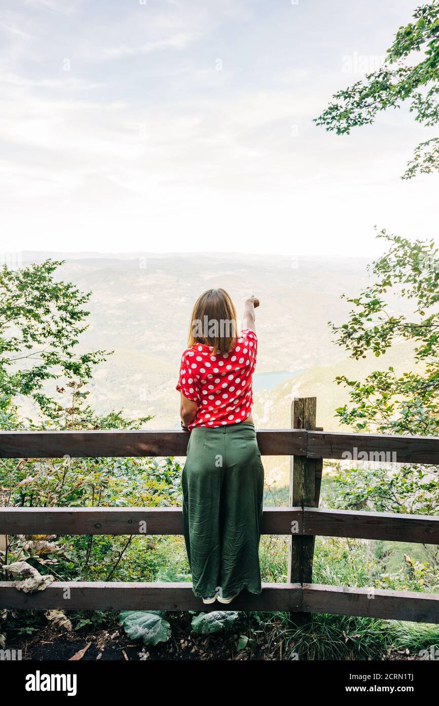 Young female nature explorer enjoying the view from mountain viewpoint Stock Photo