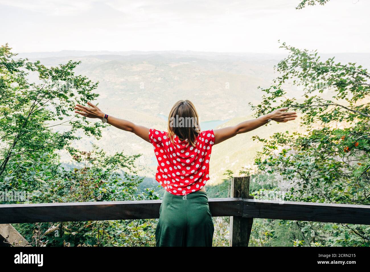 Young female nature explorer enjoying the view from mountain viewpoint Stock Photo