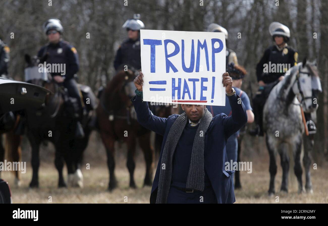 An anti-Trump protester holds his protest sign in front of mounted police outside a rally for Republican U.S. presidential candidate Donald Trump in Cleveland, Ohio, U.S. March 12, 2016.  REUTERS/Rebecca Cook/File Photo Stock Photo
