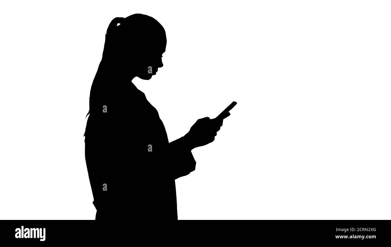 Silhouette Cheerful cute young woman doctor typing text on phone Stock Photo