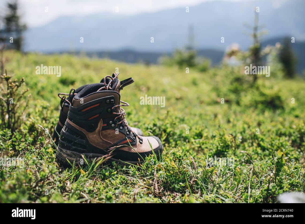 Brown hiking boots in the green grass of the Ukraninian mountains scenery Stock Photo