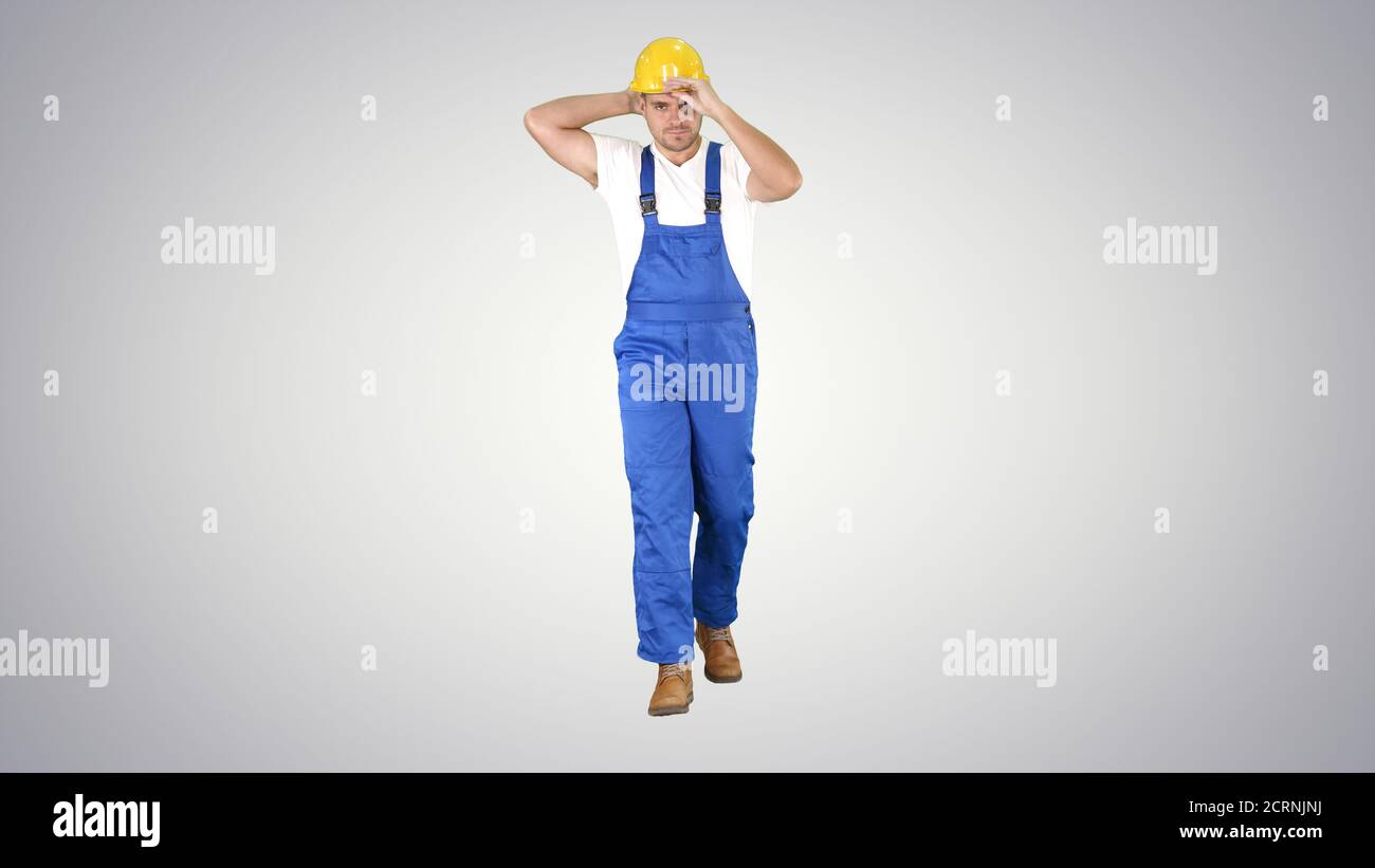 Construction worker walking and putting on hard hat or helmet on Stock Photo