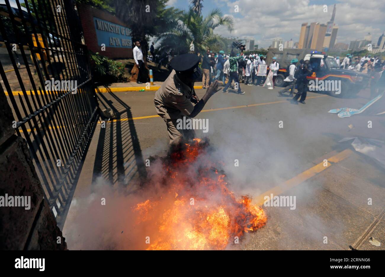 A tear gas canister fired by riot police explodes near a policeman as the police disperse doctors striking to demand fulfilment of a 2013 agreement between their union and the government that would raise their pay and improve working conditions outside Ministry of Health headquarters in Nairobi, Kenya December 5, 2016. REUTERS/Thomas Mukoya     TPX IMAGES OF THE DAY Stock Photo