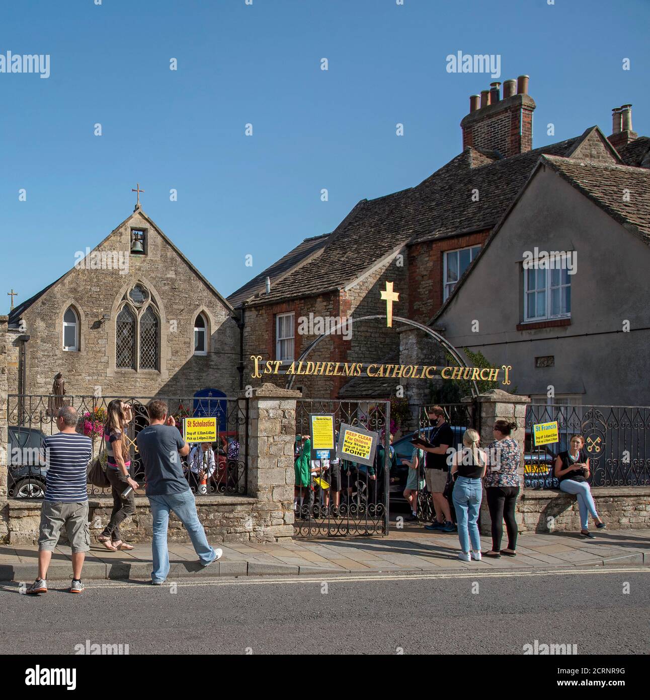 Malmesbury, Wiltshire, England, UK. 2020. Pick up point for school children during Covid-19. Parents social distancing outside St Aldhelms Catholic Ch Stock Photo