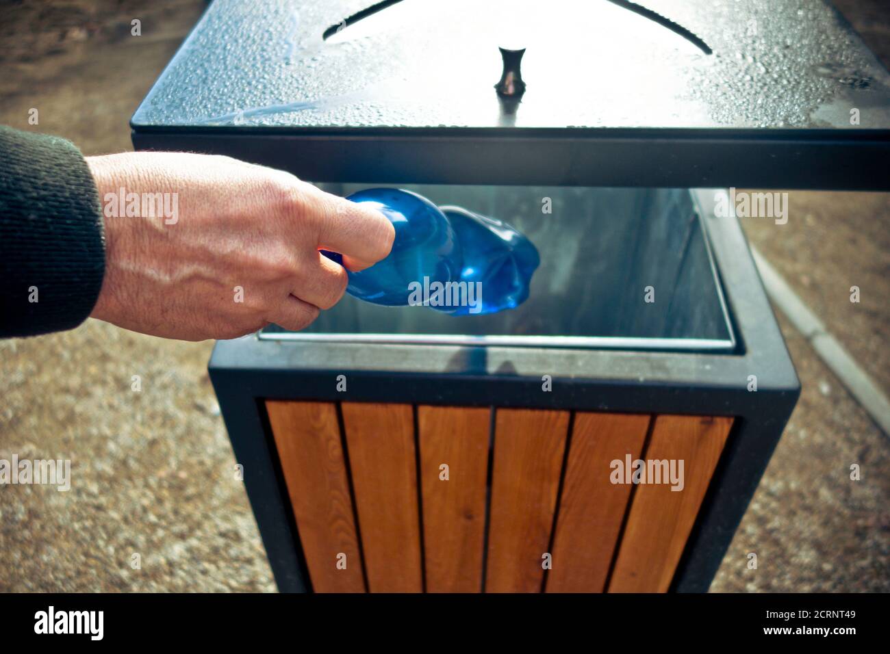 hand putting a plastic bottle into a public waste container Stock Photo