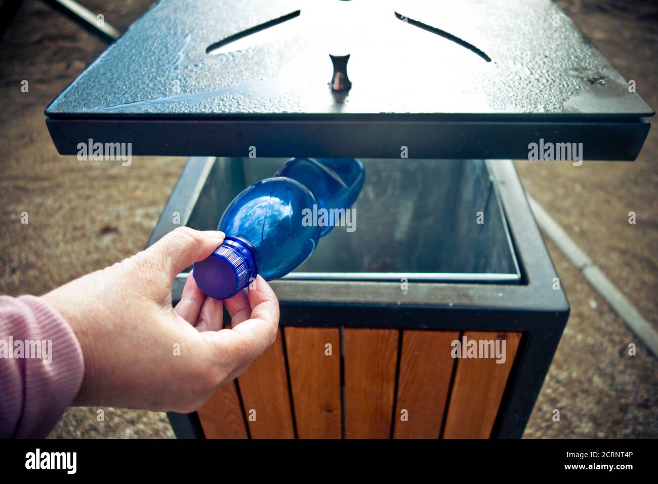 hand putting a plastic bottle into a public waste container Stock Photo