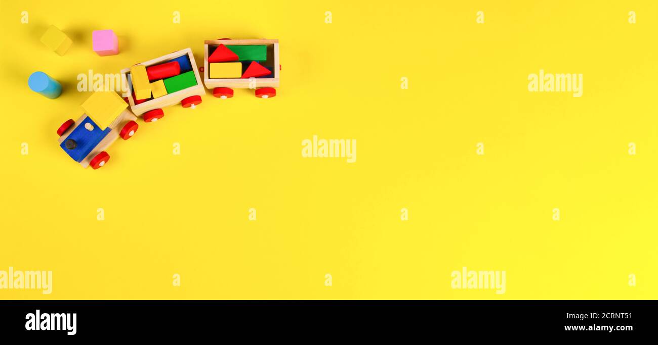 Wooden toy train with colorful blocks on yellow background. Top view