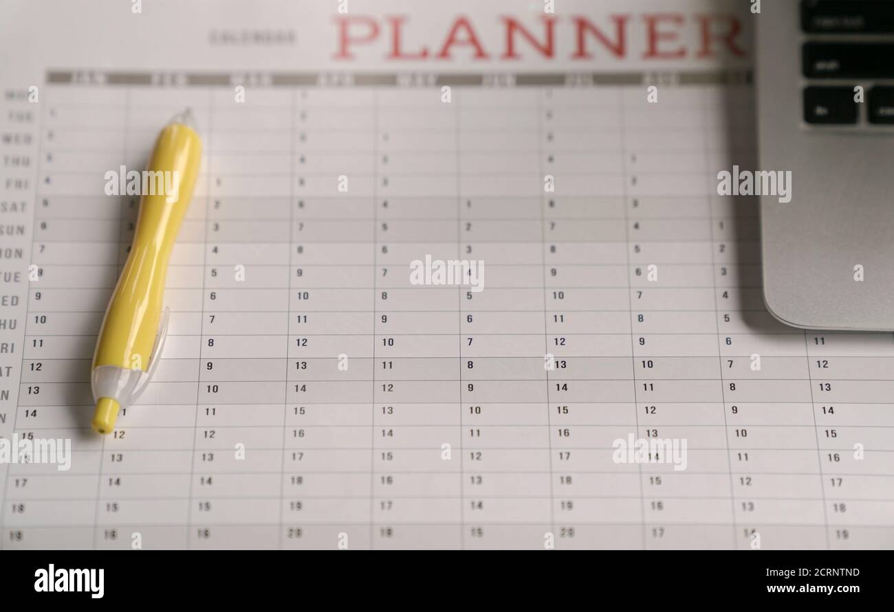Computer laptop and yellow pen on top of calendar planner Stock Photo