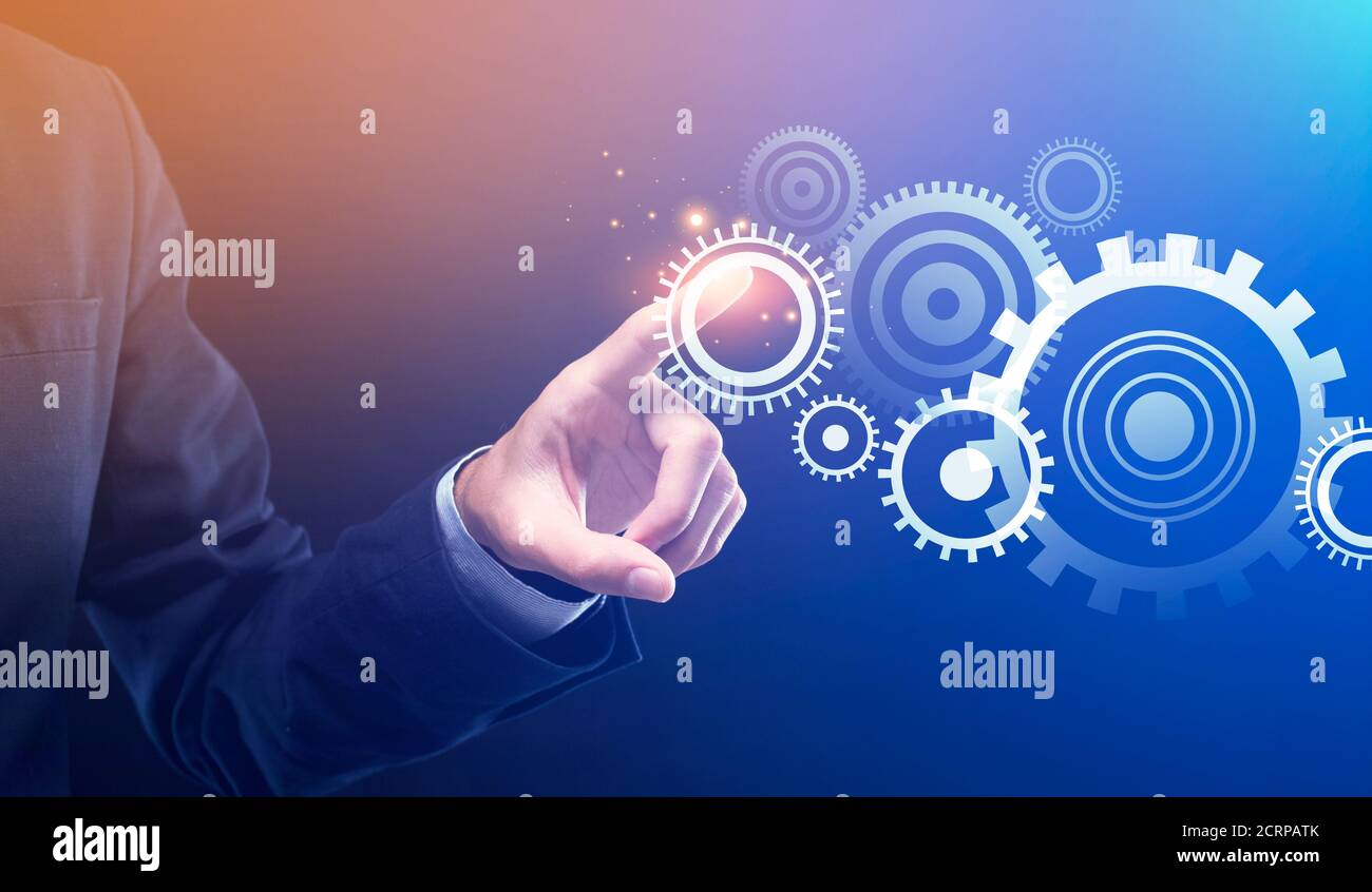 Businessman Pushing Button Turning On Cogwheels Mechanism Over Blue Background Stock Photo