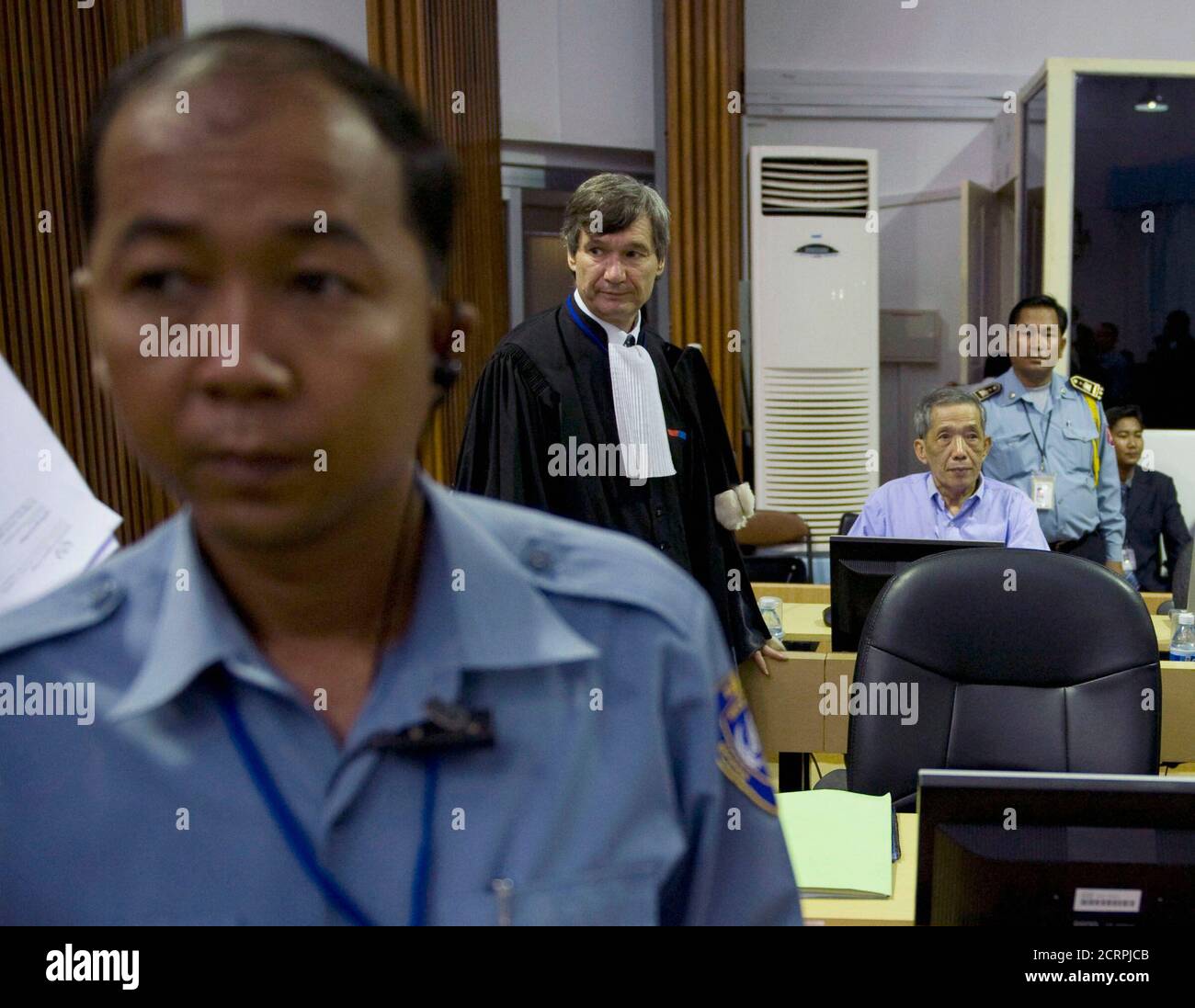 Security officials and defence attorney Francois Roux (2nd R) stand next to Kaing Guek Eav (3rd R), also known as Duch, as he awaits the start of his trial on the outskirts of Phnom Penh February 17, 2009. Duch, the ex-commandant of the notorious S-21 prison and chief Khmer Rouge torturer, faced trial for crimes against humanity on Tuesday, the first by a senior Pol Pot cadre three decades since the end of a regime blamed for 1.7 million deaths.  REUTERS/Adrees Latif   (CAMBODIA) Stock Photo