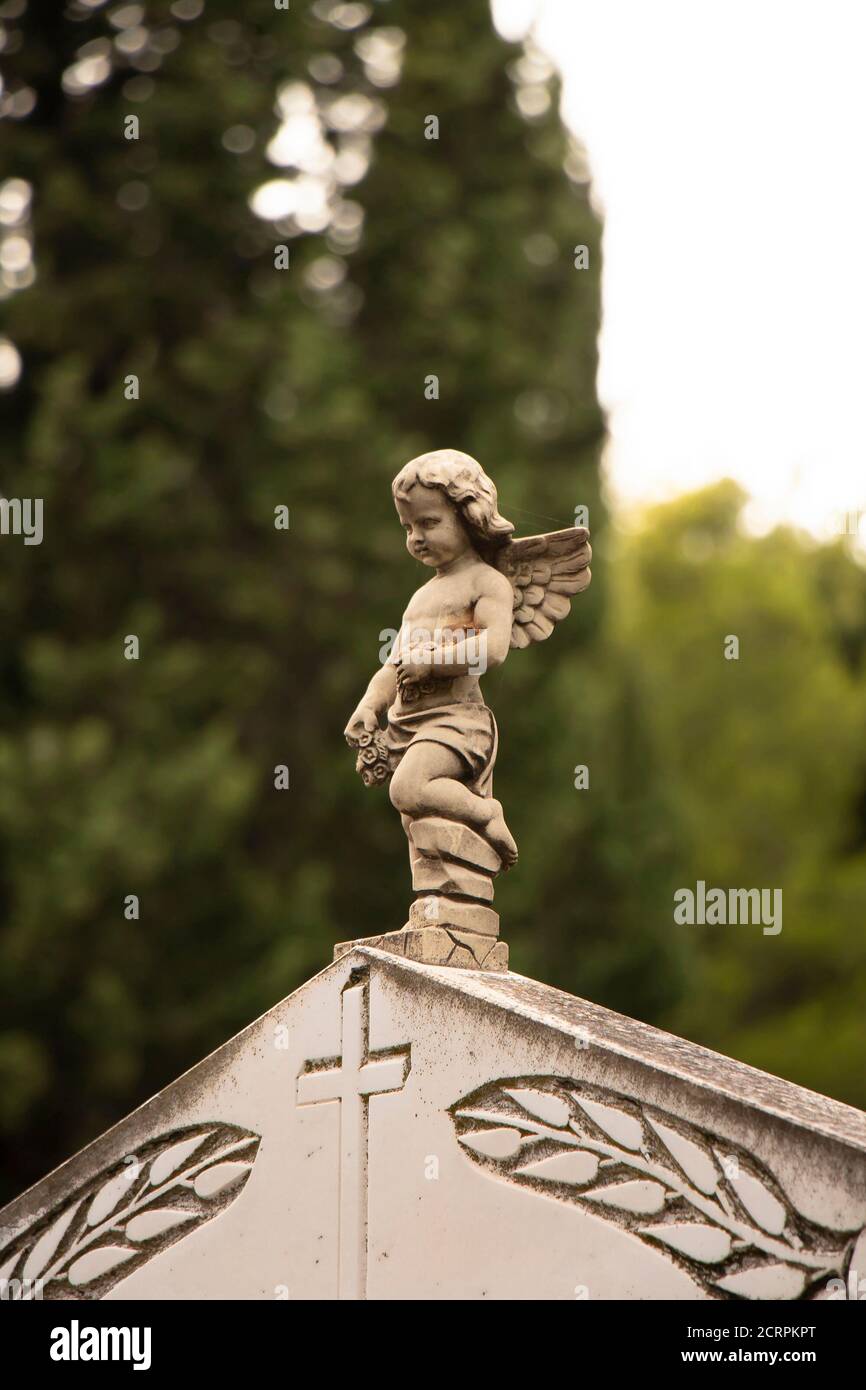 Small statue of a little angel boy with the wings  at the gravestone at the old cemetery in Dalmatia, Croatia, close up Stock Photo