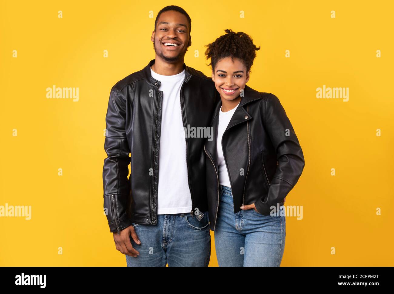 Happy African Spouses Posing Over Yellow Background, Wearing Leather Jackets Stock Photo