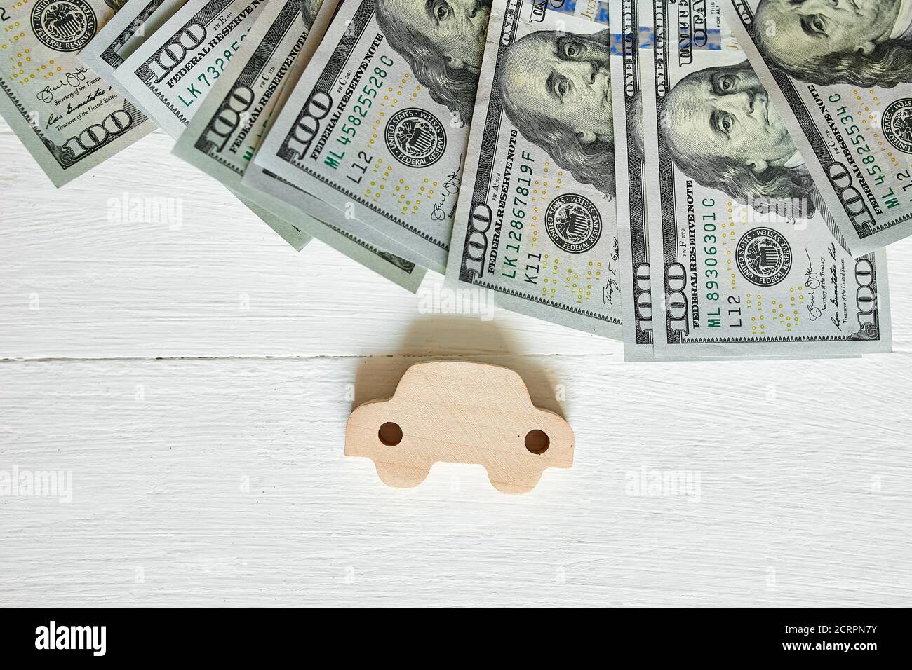 Small wooden car and hundred dollar on white background Stock Photo