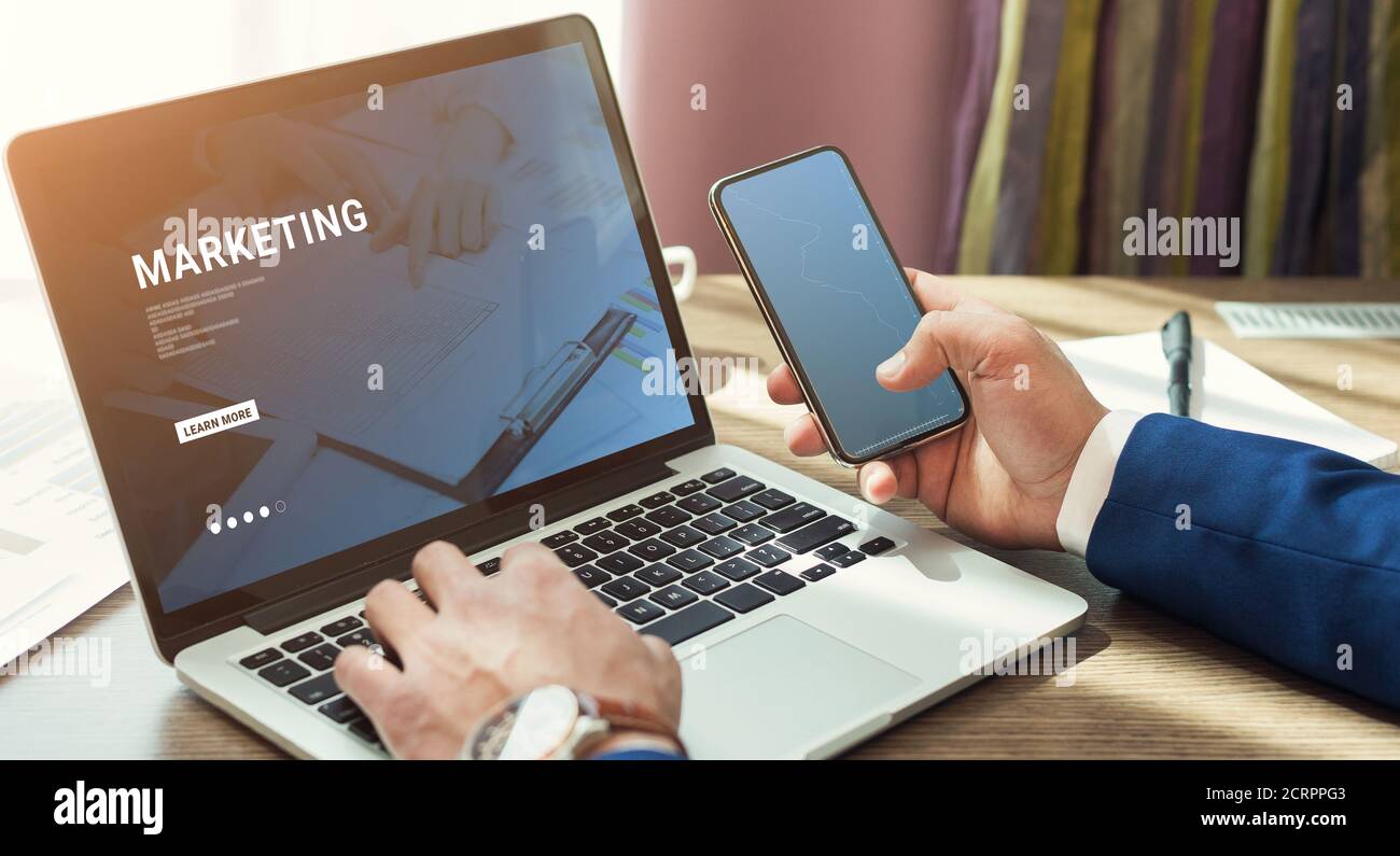 Businessman holding smartphone and using laptop Stock Photo