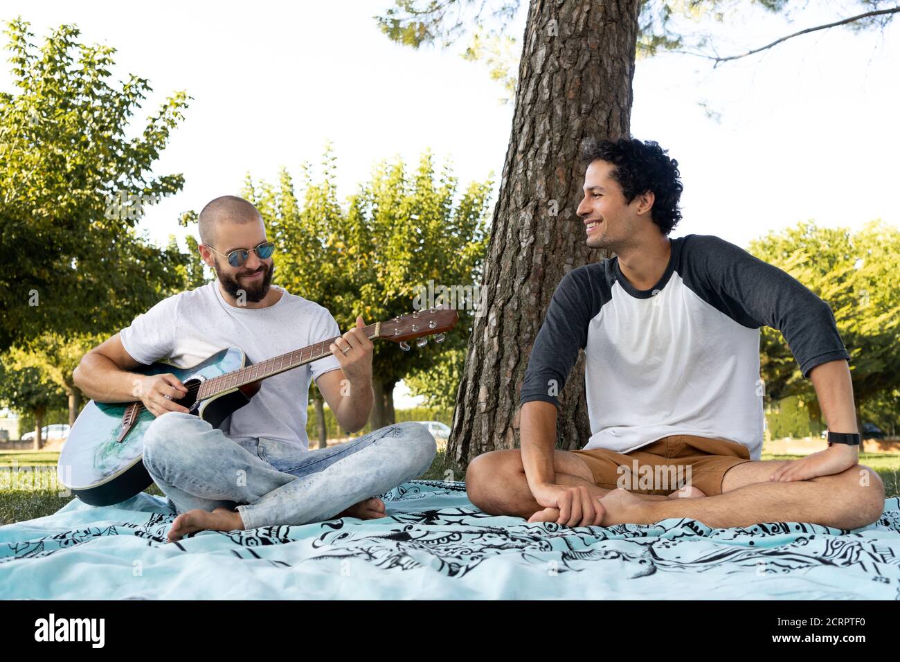 Two friends having fun and playing guitar in the park Stock Photo