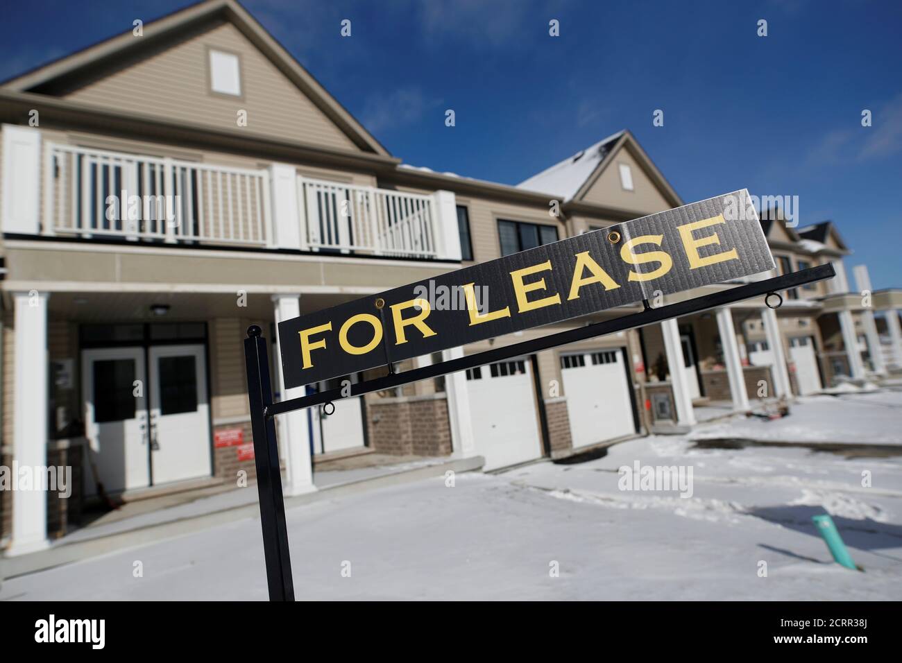 A "For lease" sign stands in front of a row of houses in a newly build