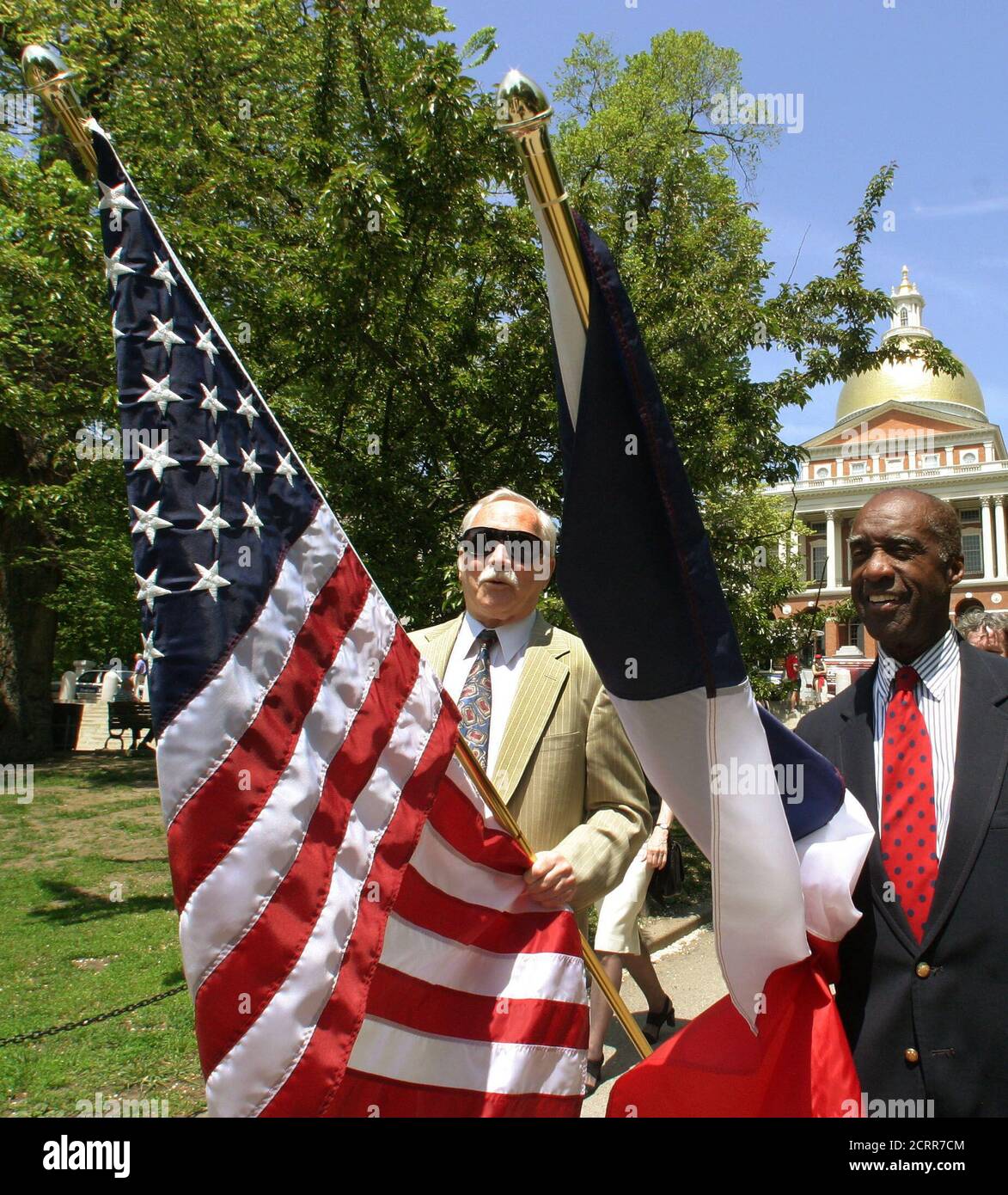 U.S. citizens John Hermanson (L) and Enoch Woodhouse (R) of the Massachusetts Lafayette society carry United States and French flags side by side from ceremonies commemorating the 169th anniversary of the death of the Marquis de Lafayette at the Massachusetts Statehouse (rear) in Boston, May 20, 2003. Lafayette was a French General and politician who became a hero in the American revolutionary war. French and local officials joined together at the event to reassert the common democratic values of the two countries despite recent diplomatic and military policy differences. REUTERS/Jim Bourg  JR Stock Photo
