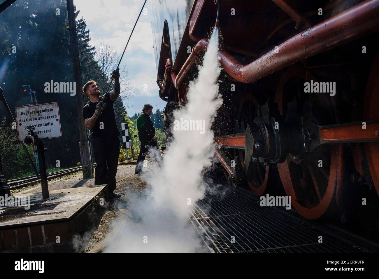 The driver of a steam locomotive of the HSB light railway prepares water tank to be refilled in Schierke in the Harz mountains, April 30, 2014. Legend has it that on Walpurgisnacht or May Eve, witches fly their broomsticks to meet the devil at the summit of the Brocken Mountain in Harz. In towns and villages scattered throughout the mountain region, locals make bonfires, dress in devil or witches costumes and dance into the new month of May. Picture taken April 30, 2014.  REUTERS/Thomas Peter (GERMANY - Tags: SOCIETY TRANSPORT) Stock Photo