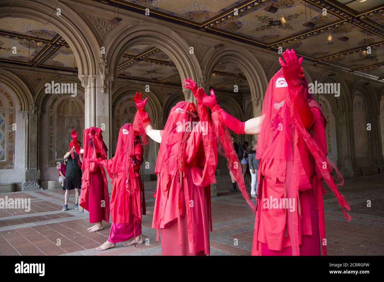 The Red Rebels, Brigade, who are a branch of Extinction Rebellion, dressed in bright red to signify the blood of species that have died as a result of climate change, as well as those that will die in the future demonstrate and march at Bethesda Fountain in Central Park organized by 'Extinction Rebellion' to bring attention to the immediate need for system change in the US and around the world to combat  the climate crisis that is now being experienced world wide in the form of wildfires, hurricanes, droughts and floods along with air and water pollution at an unprecedented scale. Stock Photo