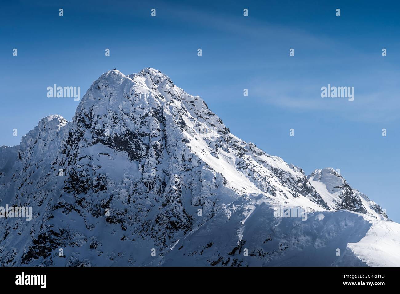 View from Kasprowy Wierch on adventurers who climbed on Swinica mountain peak at winter. Tatra Mountains range with snow capped mountain peaks, Poland Stock Photo