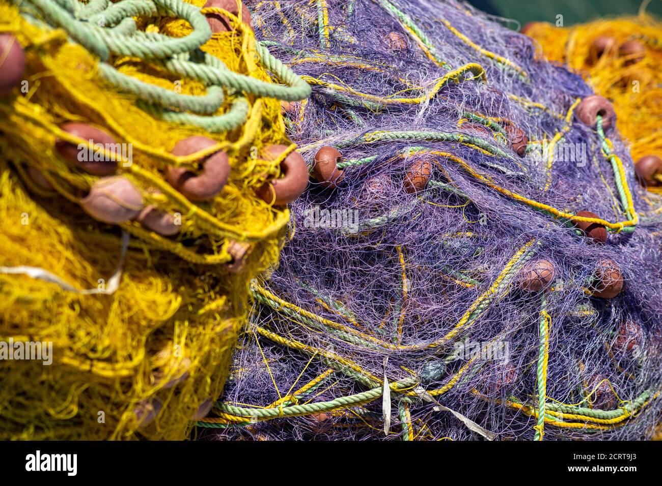Colored purple and yellow fishing nets with orange floats. Bright multi-colored backdrop. Hobby fishing concept. Selective focus. Copy space. Stock Photo