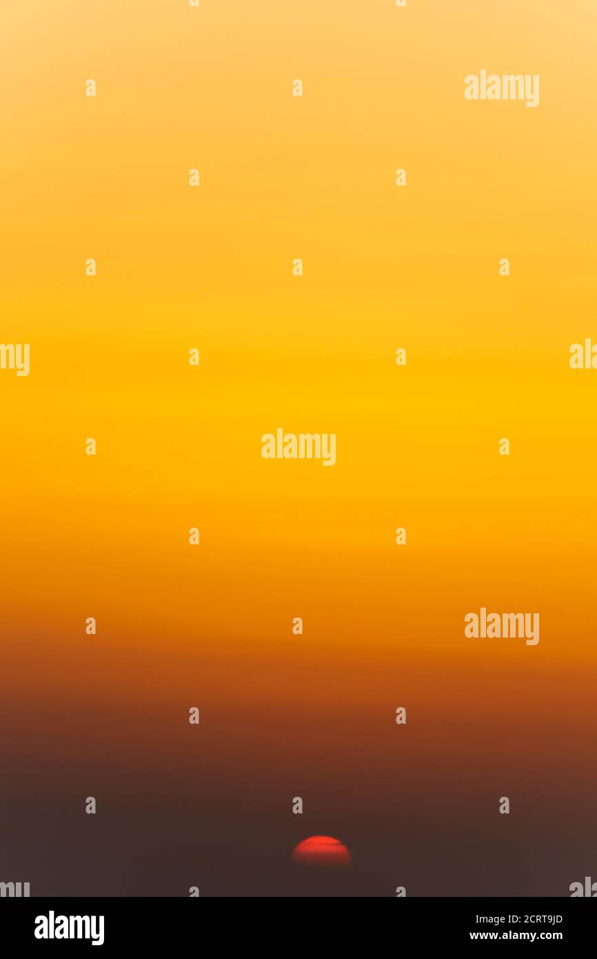 sunset over the sea. orange and yellow sky with red sun. Portrait ...