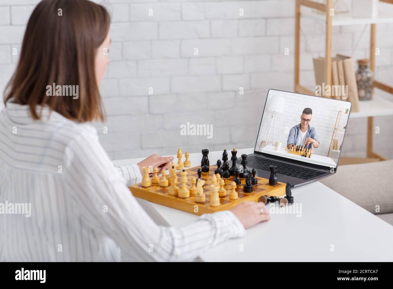 Online chess at home. Woman and guy play on board games using laptop Stock Photo