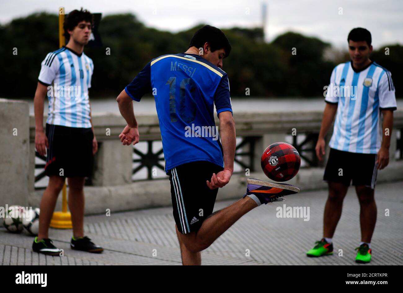 A boy wearing a Messi jersey plays with a ball before the unveiling of a statue