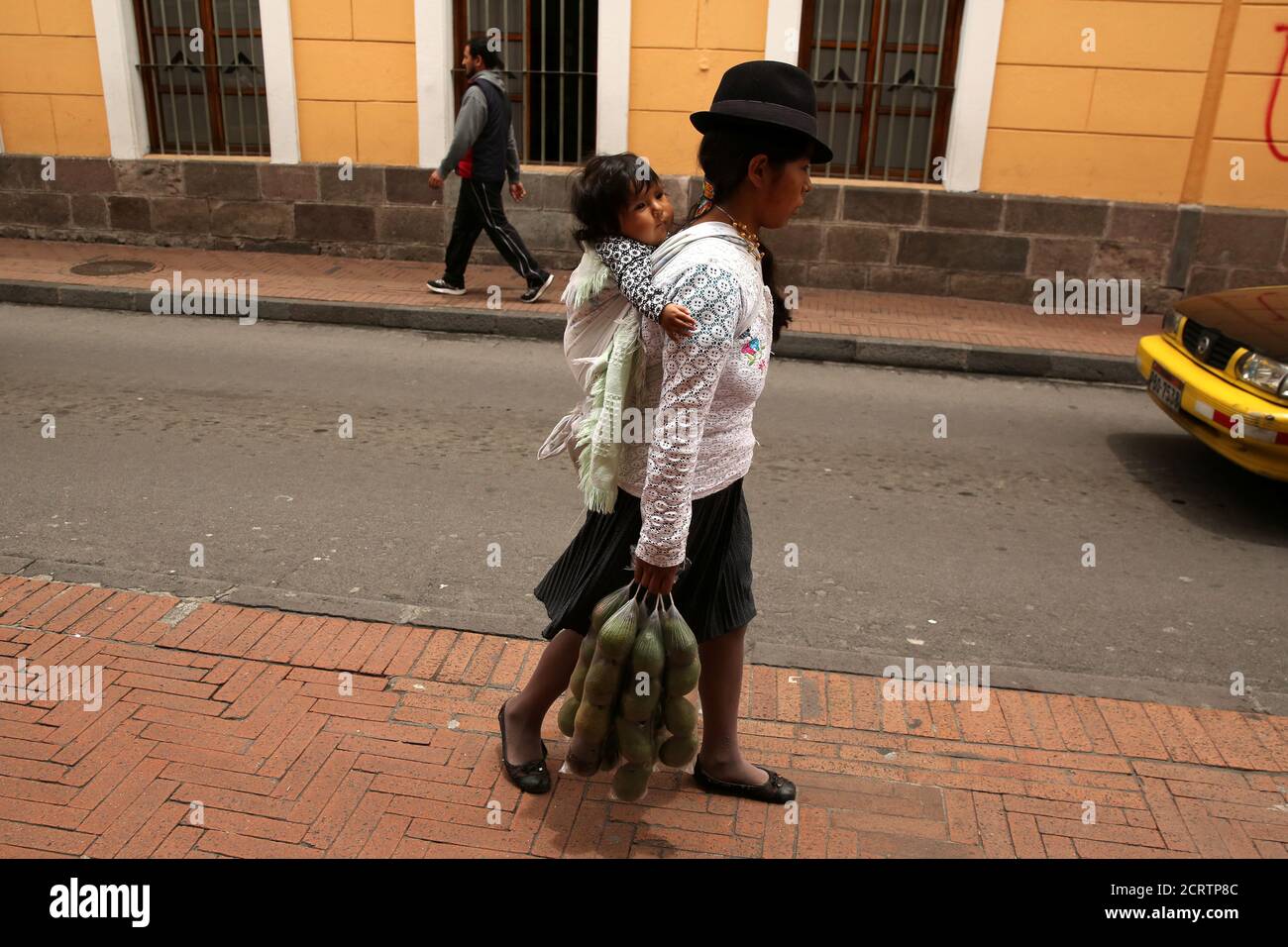 A woman carrying a baby sells avocados in downtown Quito, Ecuador March 30, 2017. REUTERS/Mariana Bazo Stock Photo