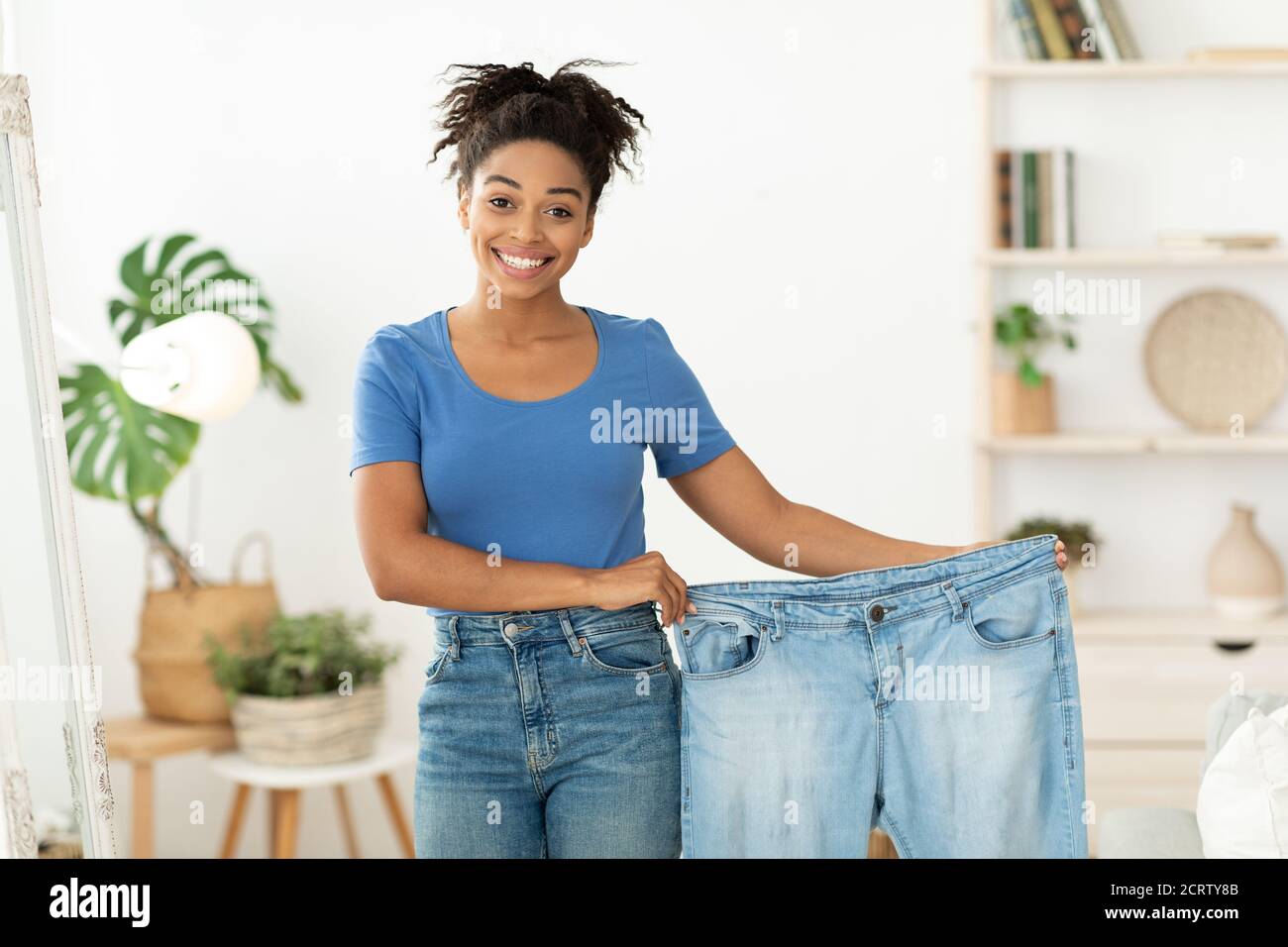 Happy Slim Black Woman Showing Old Jeans Standing At Home Stock Photo