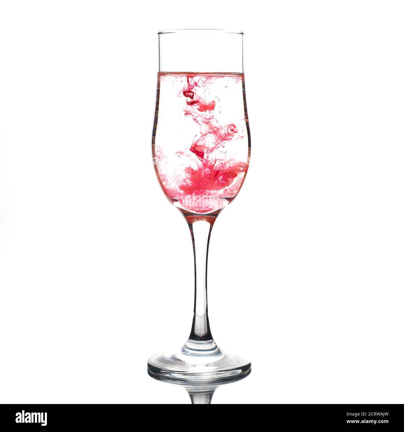 Food coloring diffuse in water inside wine glass area for slogan or advertising text message on white background Stock Photo