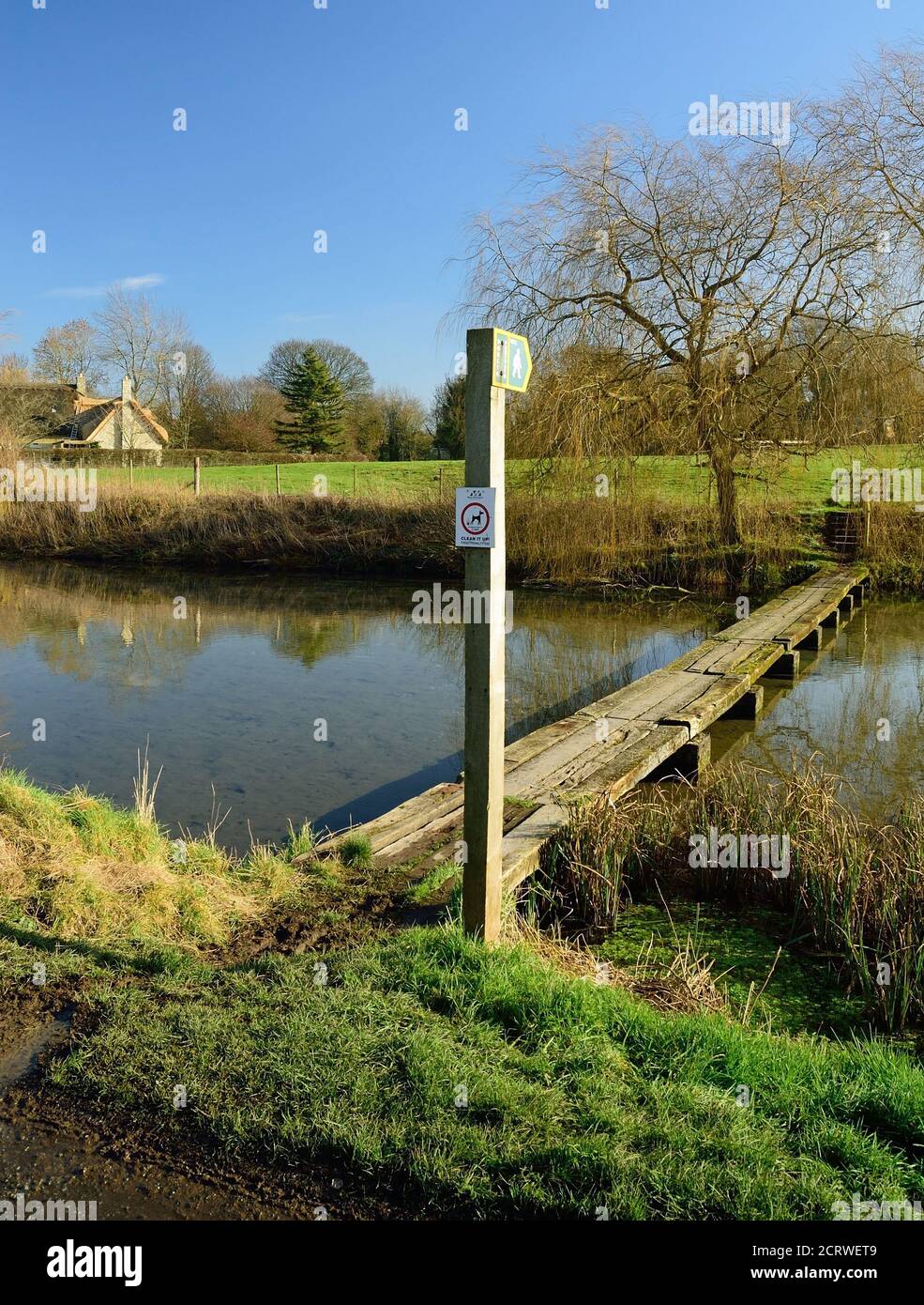 A footbridge of old railway sleepers across the mill pond in the small