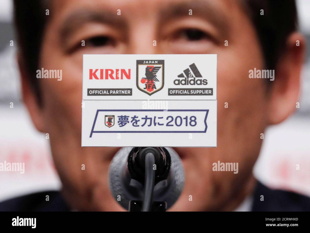 The Japan Football Association (JFA) emblem and their slogan reading "Dream  to achieve 2018" are seen in front of Japan's national soccer team's head  coach Akira Nishino during a news conference to