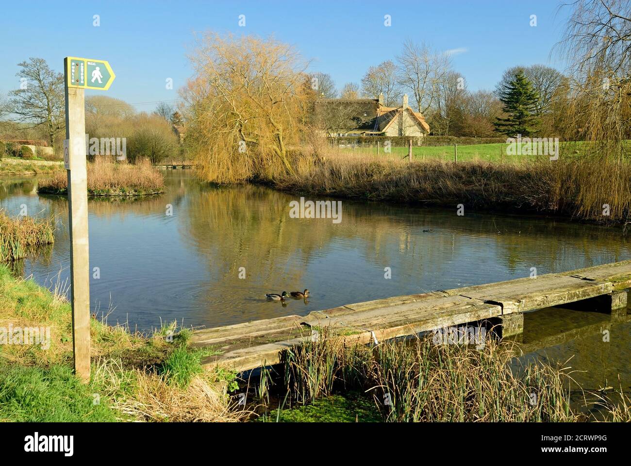 A footbridge of old railway sleepers across the mill pond in the small