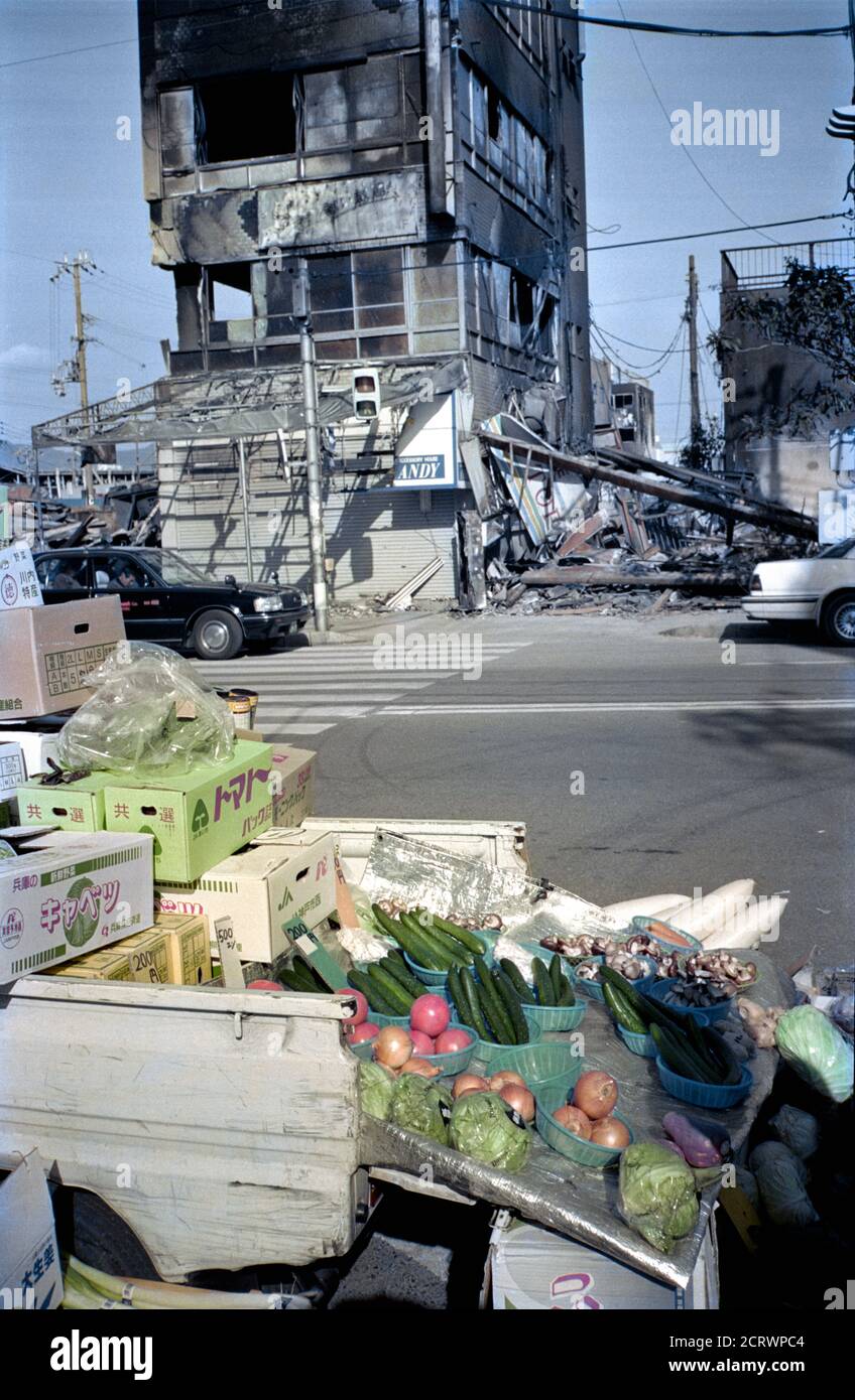 Vegetables being sold from the back of a truck in front of the burnt ruins showing the aftermath of the 1995 Great Hanshin Earthquake in Kobe, Japan Stock Photo