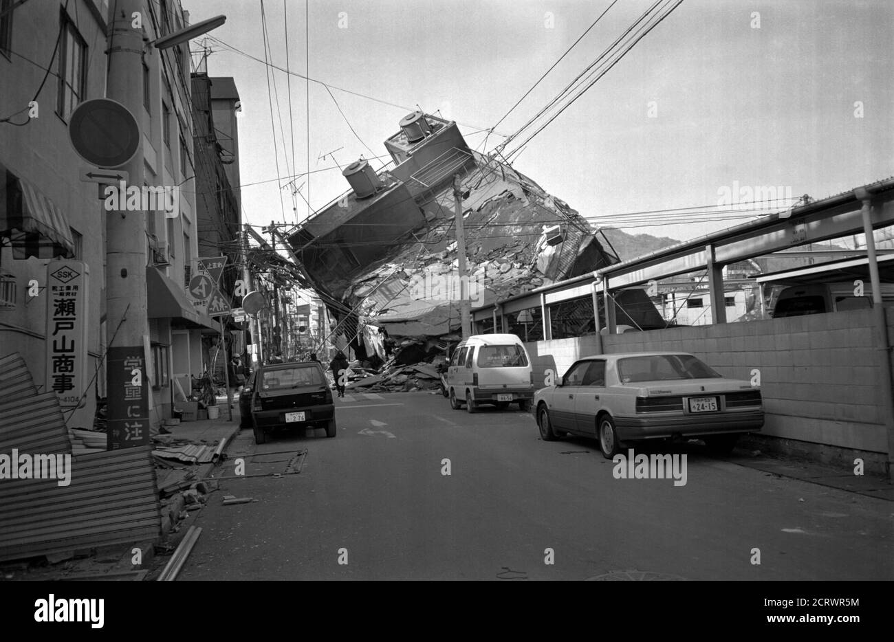 Building collapsed sideways down the road from the damage caused by the 1995 Great Hanshin Earthquake in Kobe, Japan Stock Photo