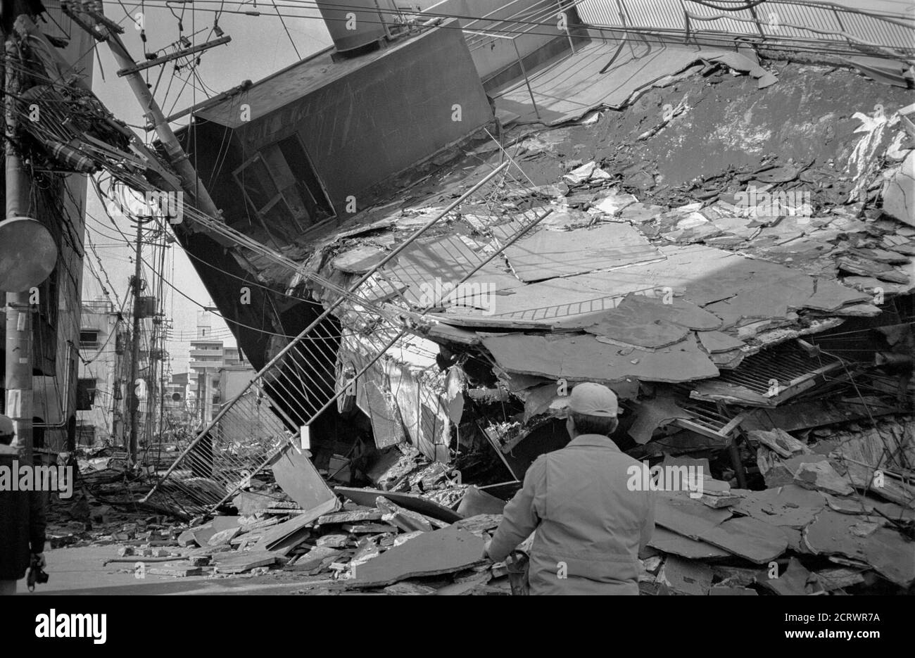 Man stops and looks upon collapsed building from the damage caused by the 1995 Great Hanshin Earthquake in Kobe, Japan Stock Photo